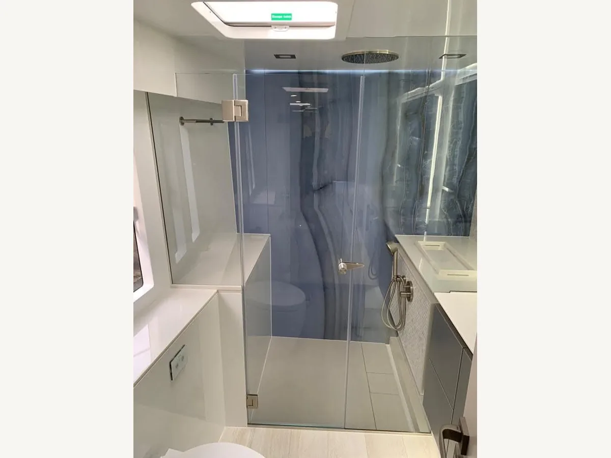 Baño del yate terminado, con mampara de ducha de cristal y mueble de lavabo integrado